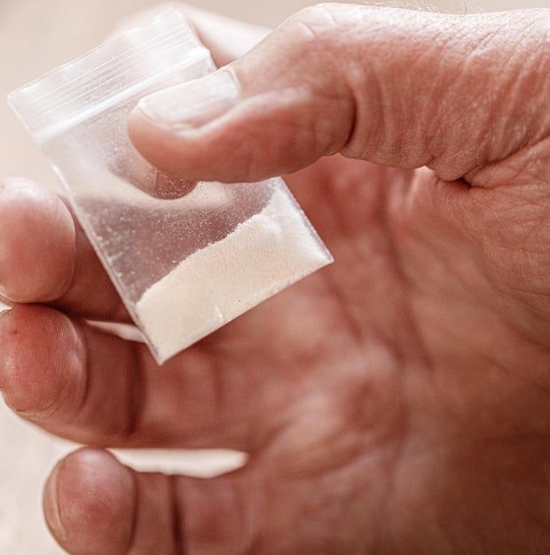 fentanyl heroin opiate powder cocaine in plastic bag in hand close-up