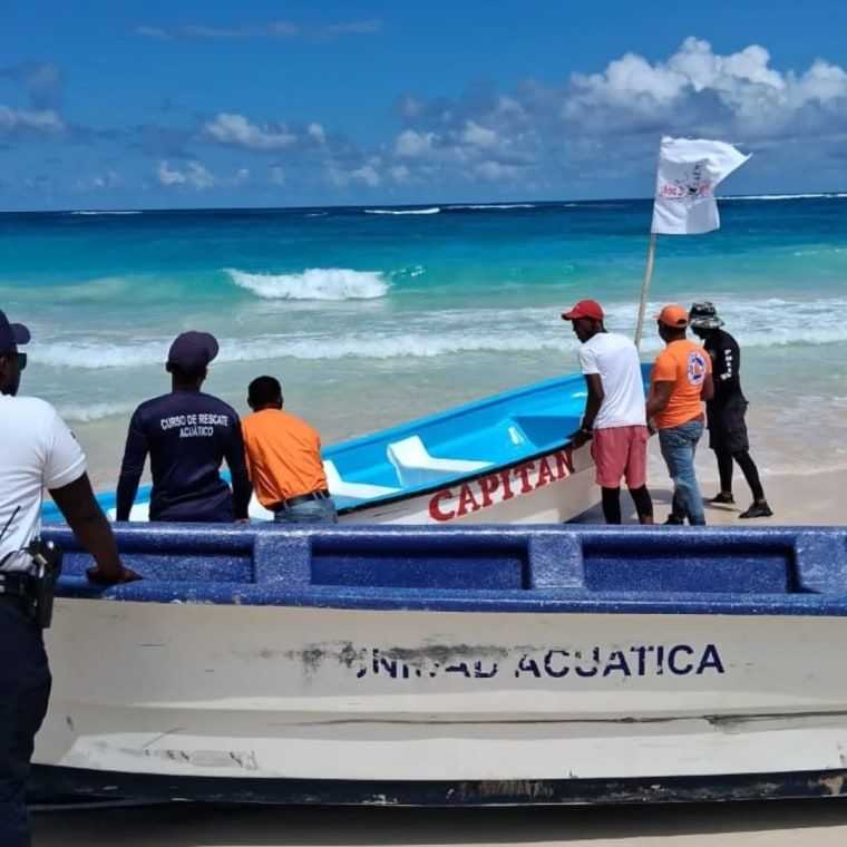 Witness says missing Pitt student rescued from powerful wave — then vanished 1 People gather in a group to search on a beach shore, they carry boats to the water