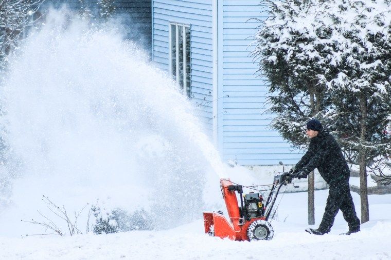 Travel disruptions mount as strong storm system sweeps across the country 2 A man removes snow with a snowblower outside