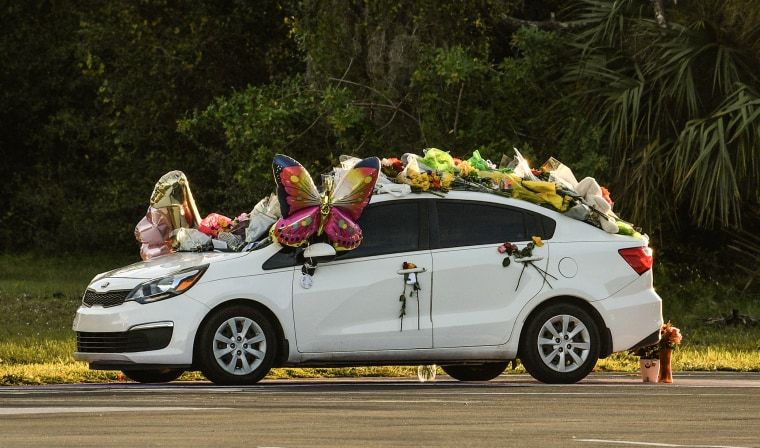 Judge declines to jail teenager accused killing stepsister aboard cruise ship 3 A white sedan, covered in mylar balloons and flower bouquets, at sunset.