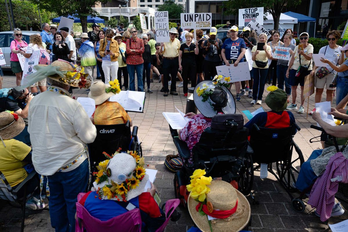 Video: Large Protests Flood Streets to Denounce Trump 1 A group of people, shown from behind, reading music from a stand while sitting.